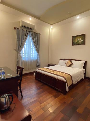a bedroom with a bed and a desk and a window at KIM BĂNG HOTEL BÌNH DƯƠNG in Thu Dau Mot