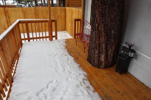 een veranda met sneeuw op de vloer naast een boom bij The Blue Lake Cabin! 1 min Walk to SnowPlay! in Big Bear City