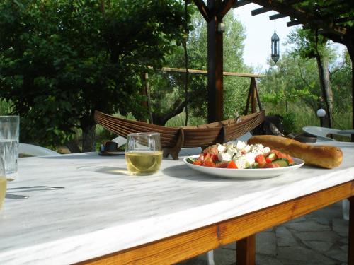 a table with a plate of food and a glass of wine at Bozelia Apartments in Toroni