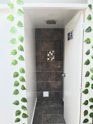 a bathroom with a shower with green leaves on the wall at CASA DE LOURDES - LA CANDELARIA in Bogotá