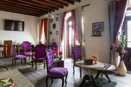 sala de estar con sillas de color púrpura y mesa en Hotel Colonial San Agustin, en Quito