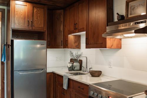 La cuisine est équipée d'armoires en bois et d'un réfrigérateur en acier inoxydable. dans l'établissement Rosedale Chapel Bed and Breakfast, à Steinbach