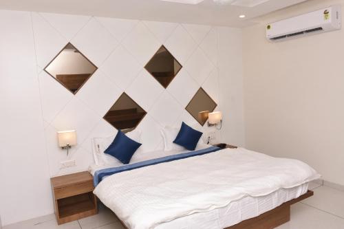 a bedroom with a large white bed with blue pillows at HOTEL GOLDEN PALACE & ROOMS in Hālol