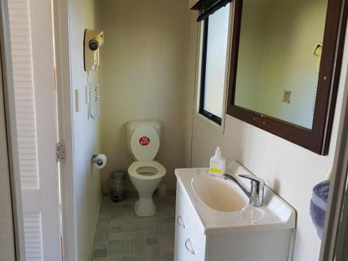 a small bathroom with a toilet and a sink at Te Puru Holiday Park in Thames