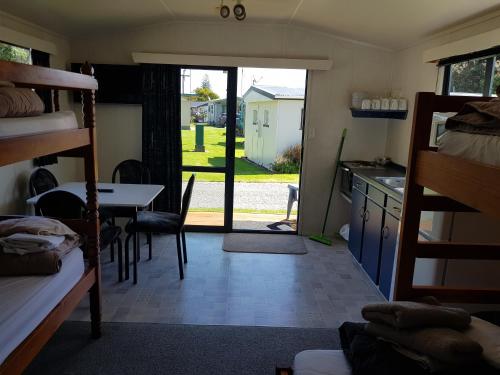 a room with a bed and a table and a kitchen at Te Puru Holiday Park in Thames