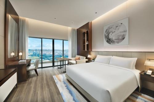 a hotel room with a large bed and a desk at Oakwood Residence Foshan in Foshan