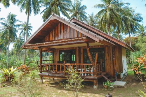 a small wooden house with palm trees in the background at Kohjum Freedom Resort in Ko Jum