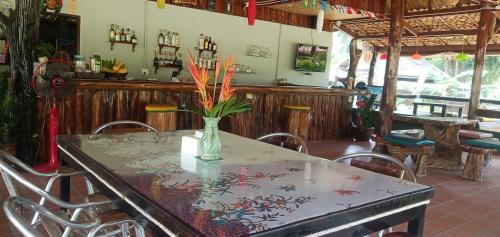 a table in a restaurant with a vase with flowers on it at Kohjum Freedom Resort in Ko Jum