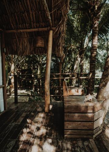 a wooden porch with a straw roof and a tree at BOA BOA Bacalar in Bacalar