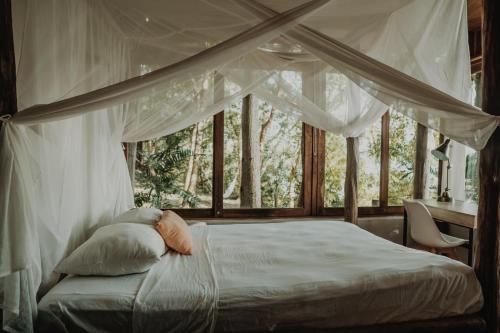 a bedroom with a canopy bed in front of a window at BOA BOA Bacalar in Bacalar