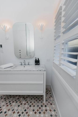 a white bathroom with a sink and a mirror at Mopsy's On The Esplanade in Wagga Wagga