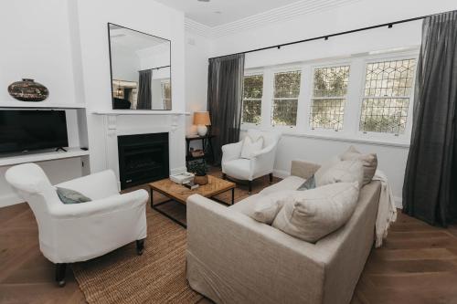 ein Wohnzimmer mit weißen Möbeln und einem Kamin in der Unterkunft Mopsy's On The Esplanade in Wagga Wagga
