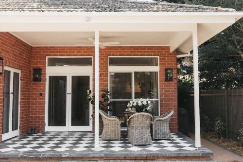 a brick house with a patio with wicker chairs at Mopsy's On The Esplanade in Wagga Wagga