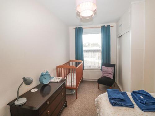 a bedroom with a crib and a bed and a chair at Dunholme House in Teignmouth