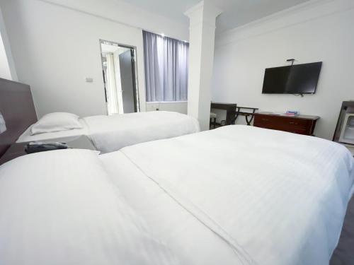 a hotel room with two beds and a flat screen tv at Guide Hotel Kaohsiung Liuhe in Kaohsiung