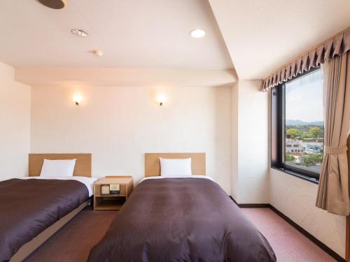 een slaapkamer met twee bedden en een groot raam bij Hotel Primrose Saito in Saito