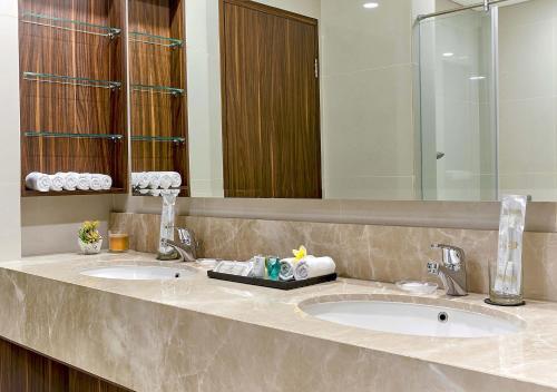 baño con 2 lavabos y espejo grande en Le Premier Hotel Deltamas, en Cikarang