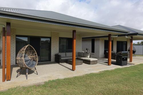 a house with a patio with a couch and a chair at Bali Elliott Heads - Coastal Holiday Home near Boat Ramp in Elliott Heads