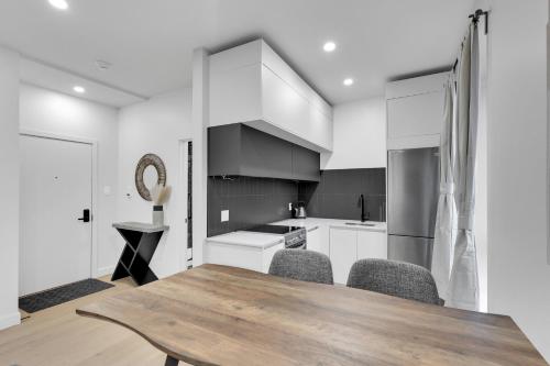 a kitchen with white cabinets and a wooden table and chairs at Deluxe Suites Downtown Montreal in Montréal