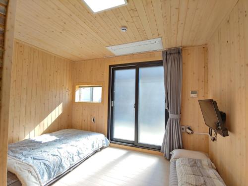 1 dormitorio con 1 cama, TV y ventana en Gentle Resort, en Jeju