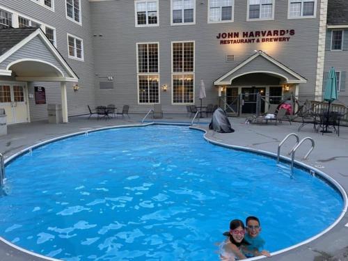 two people laying in a swimming pool in front of a building at Mountain View Suite Sleeps 4 Ski OnOff Jiminy Peak in Hancock