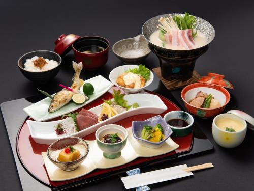 a table with plates of food and bowls of food at Hotel Primrose Saito in Saito