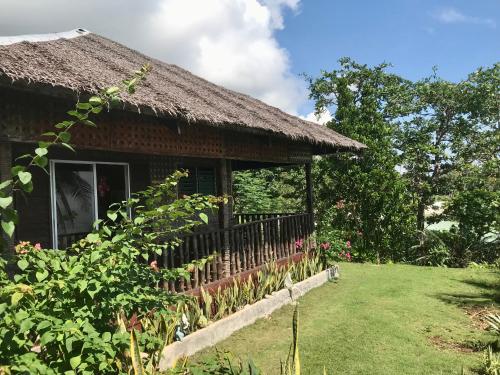 a house with a thatch roof and a yard at Camotes Cay Hideaway in San Francisco