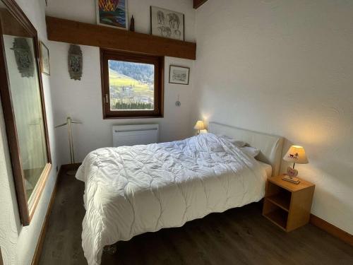 a bedroom with a bed with a white comforter and a window at Charmant 2P cabine 35m², proche pistes et village, parking, 4 pers. - FR-1-603-71 in Praz-sur-Arly
