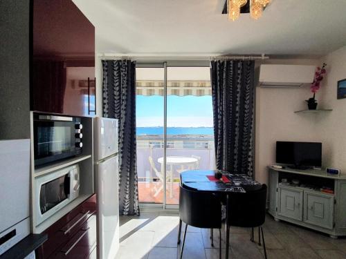 une cuisine avec une table et une vue sur un balcon dans l'établissement Appartement climatisé, proche thermes, garage privé, Wi-Fi - Balaruc-les-Bains - FR-1-503-160, à Balaruc-les-Bains