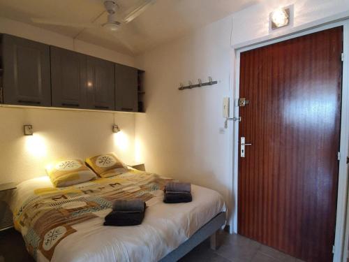 une chambre avec un grand lit et une porte en bois dans l'établissement Appartement climatisé, proche thermes, garage privé, Wi-Fi - Balaruc-les-Bains - FR-1-503-160, à Balaruc-les-Bains