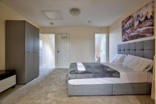 een slaapkamer met een groot bed en een schilderij aan de muur bij Free Parking - Large House - Contractor - Leisure in Peterborough