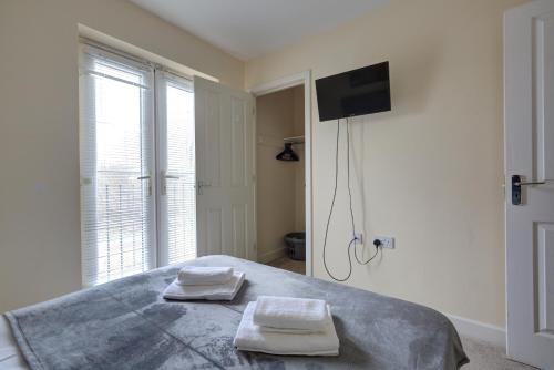 een slaapkamer met een bed met twee handdoeken erop bij Free Parking - Large House - Contractor - Leisure in Peterborough