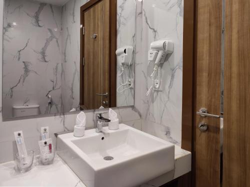 bagno con lavandino bianco e specchio di UNHAS HOTEL & CONVENTION a Patjinongong