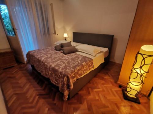 um quarto com uma cama e um candeeiro num piso de madeira em Apartments Srđan - 10 m from beach em Vinišće