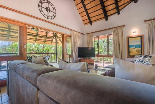 a living room with a bed and a tv and windows at Kruger Park Lodge Unit No. 241 in Hazyview