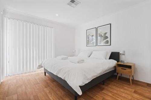 a white bedroom with a large bed and a wooden floor at Villa on Valcross in Dunsborough