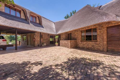 a brick house with a thatched roof and a driveway at Kruger Park Lodge Unit No. 241 in Hazyview