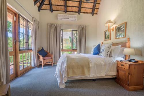- une chambre avec un grand lit blanc et des fenêtres dans l'établissement Kruger Park Lodge Unit No. 241, à Hazyview
