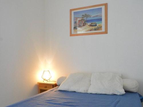 une chambre avec un lit et un tableau au mur dans l'établissement Cap d'Agde : T2 avec piscine, parking, à 50m de la plage - FR-1-249-71, au Cap d'Agde