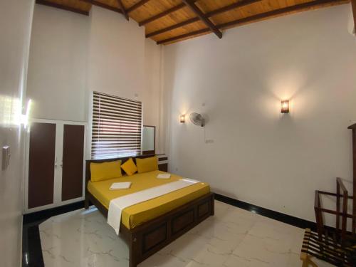 um quarto com uma cama com almofadas amarelas em The Kingslayer Resort em Negombo
