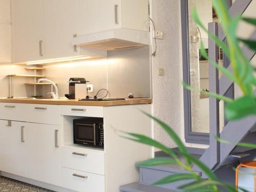 une cuisine avec des armoires blanches et un micro-ondes dans l'établissement Appartement 3 pièces climatisé, terrasse, 6 couchages, parking privé, animaux admis - FR-1-326-673, à Marseillan