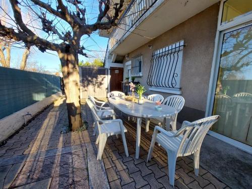 une table blanche et des chaises sur une terrasse dans l'établissement Appartement 3 pièces RDC 8 pers avec Terrasse et Confort Modeste - FR-1-326-738, à Marseillan