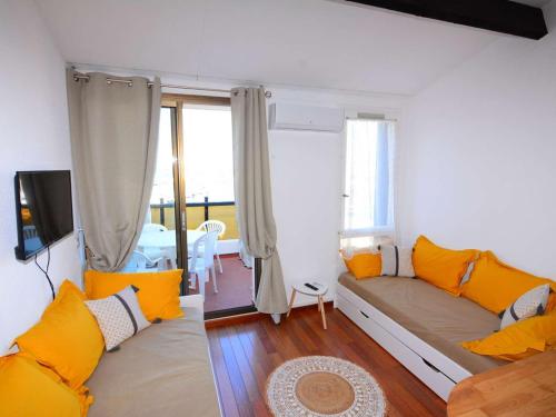 a living room with a couch with orange pillows at Appartement Le Barcarès, 2 pièces, 4 personnes - FR-1-431-181 in Le Barcarès
