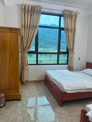 a bedroom with a bed and a large window at Minh Vân Hostel in Ha Giang