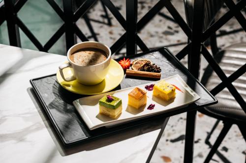 a cup of coffee and a plate of desserts on a table at Mercure Singapore Tyrwhitt in Singapore