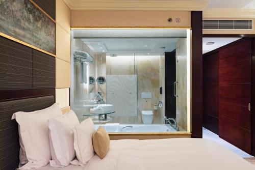 a bedroom with a bath tub and a bed with pillows at StarWorld Hotel in Macau