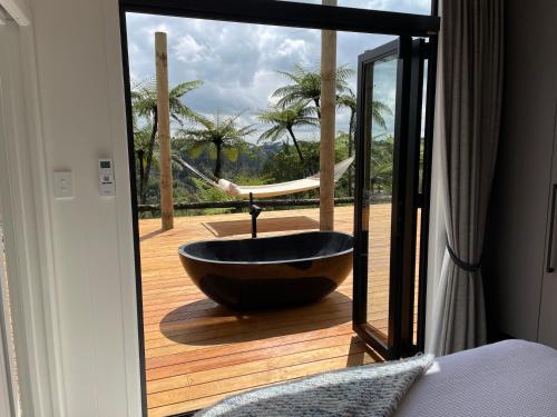 a bath tub sitting on a deck with a glass door at Pukeko Lane in Tauranga