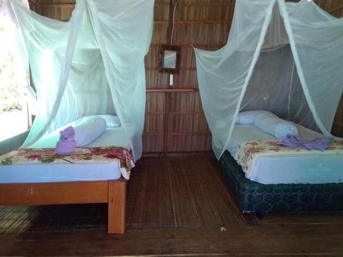 2 camas en una habitación con cortinas en Yenbainus homestay, en Yennanas Besir