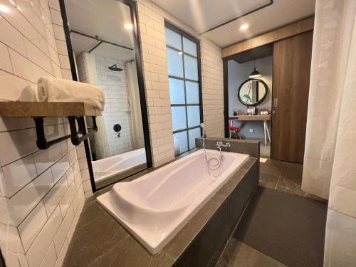 a large bathroom with a tub and a mirror at Hotel Fortunagrande Jember in Jember