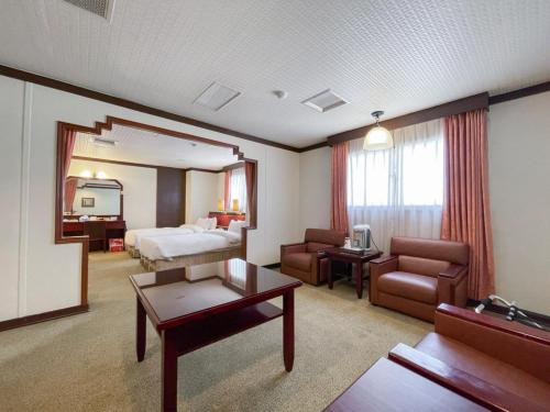 彰化市にあるGuide Hotel Changhua Jhongjhengのベッドとリビングルームが備わるホテルルームです。